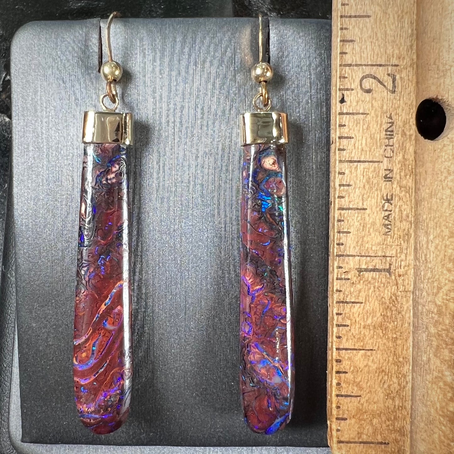 A pair of yellow gold cap Koroit boulder opal dangle earrings. Purple highlights are seen.