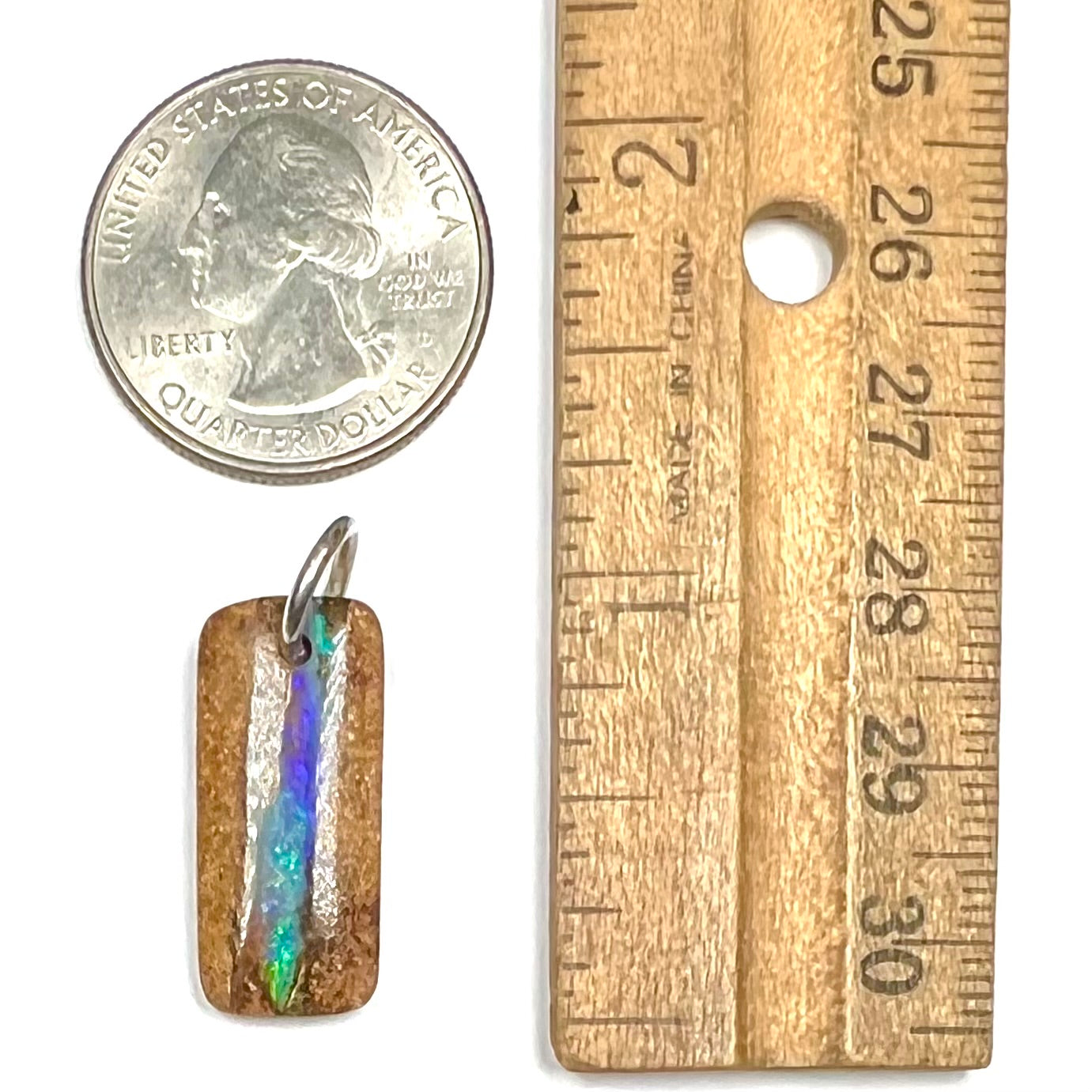 A drilled boulder opal stone with a sterling silver ring through the hole to be worn as a pendant.