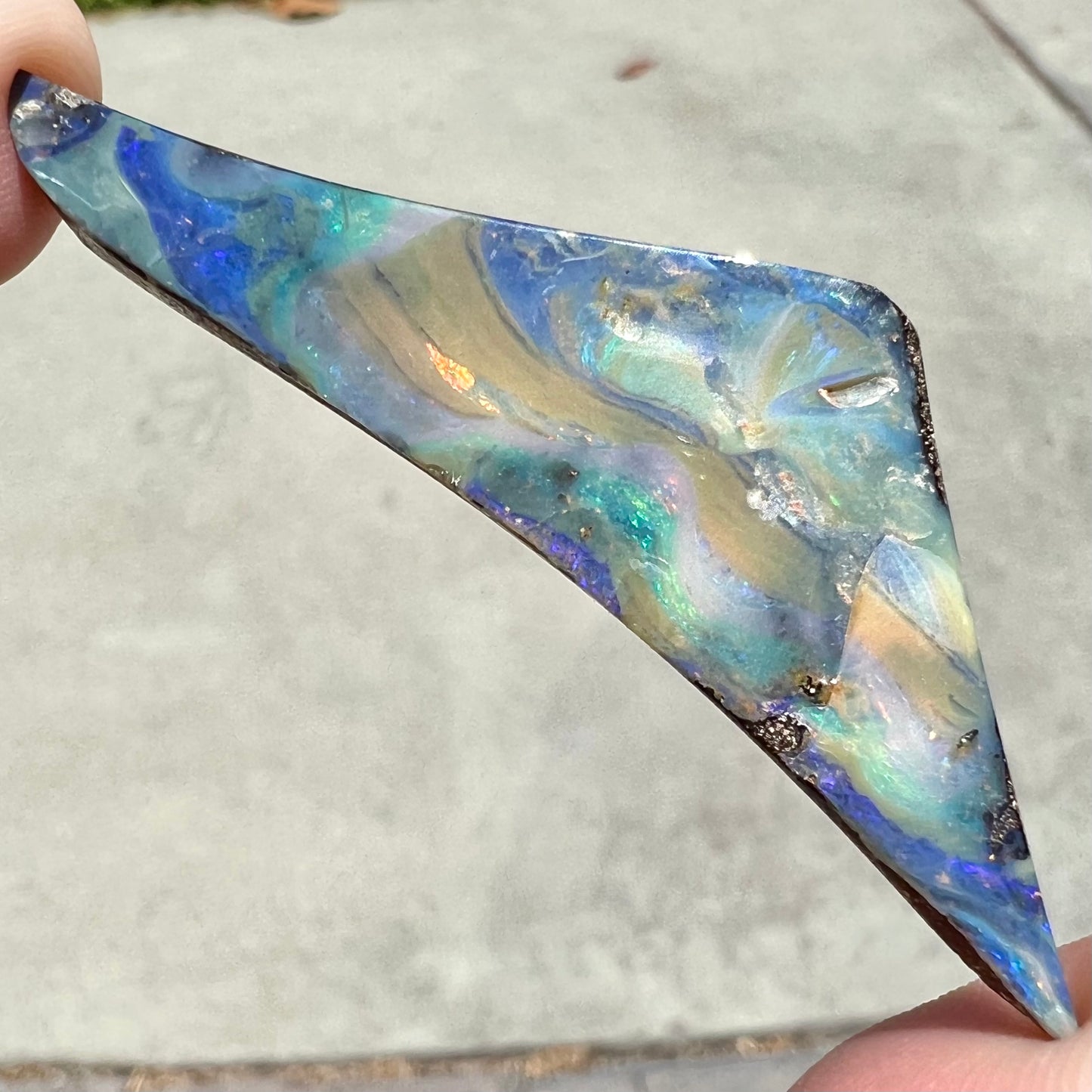 A loose, triangular shaped boulder opal stone from Queensland, Australia.