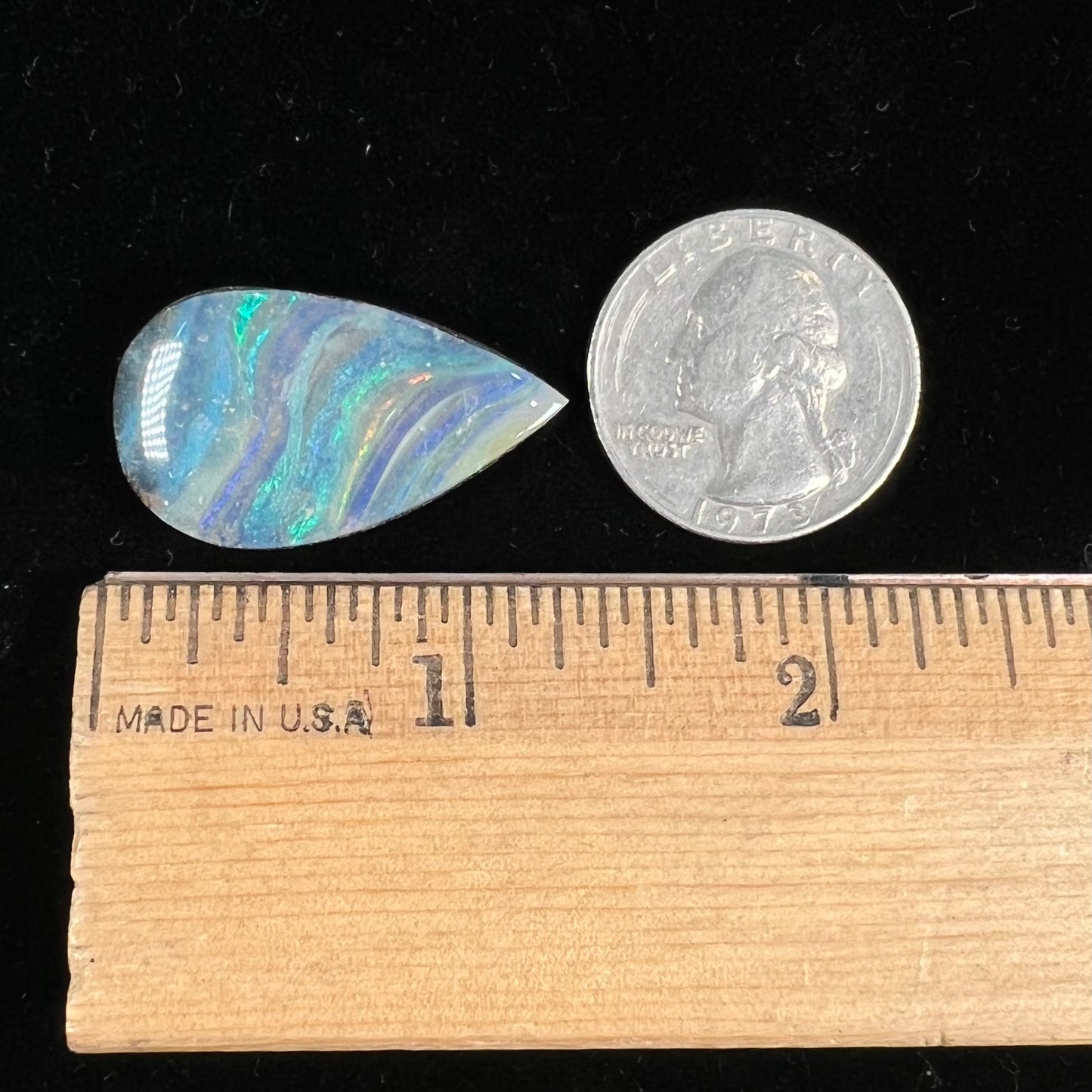 A loose, pear shaped boulder opal stone from Quilpie, Australia. The stone is predominantly blue, green, and purple with red and orange undertones.