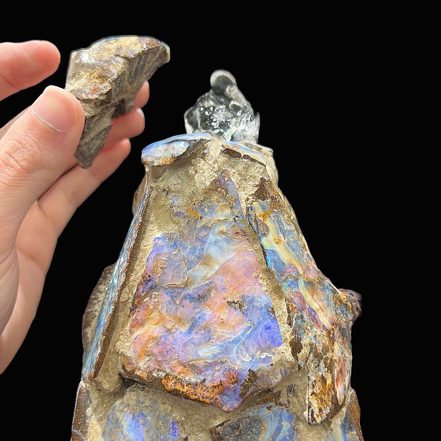 An indoor/outdoor three sided pyramid fountain made from Australian boulder opal, sitting in a bowl of Mexican fire opal.