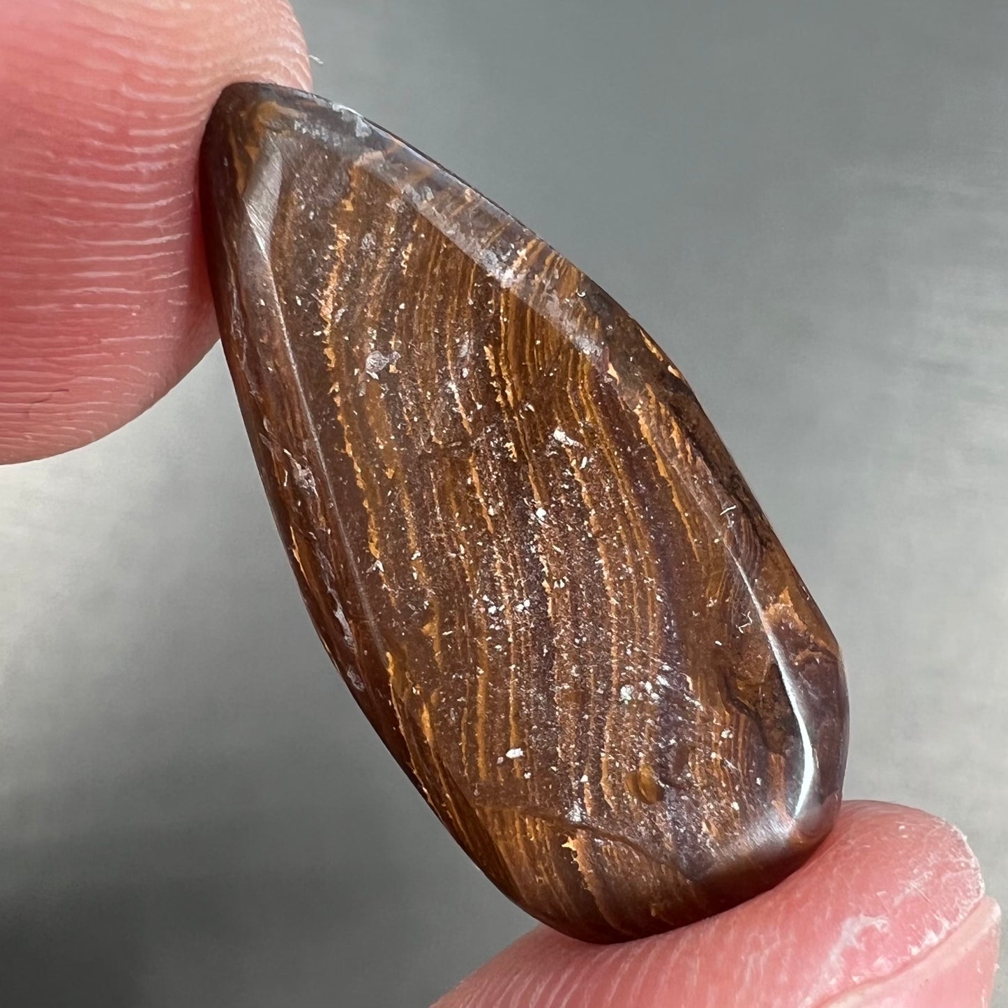 A loose, teardrop shaped purple boulder opal stone.