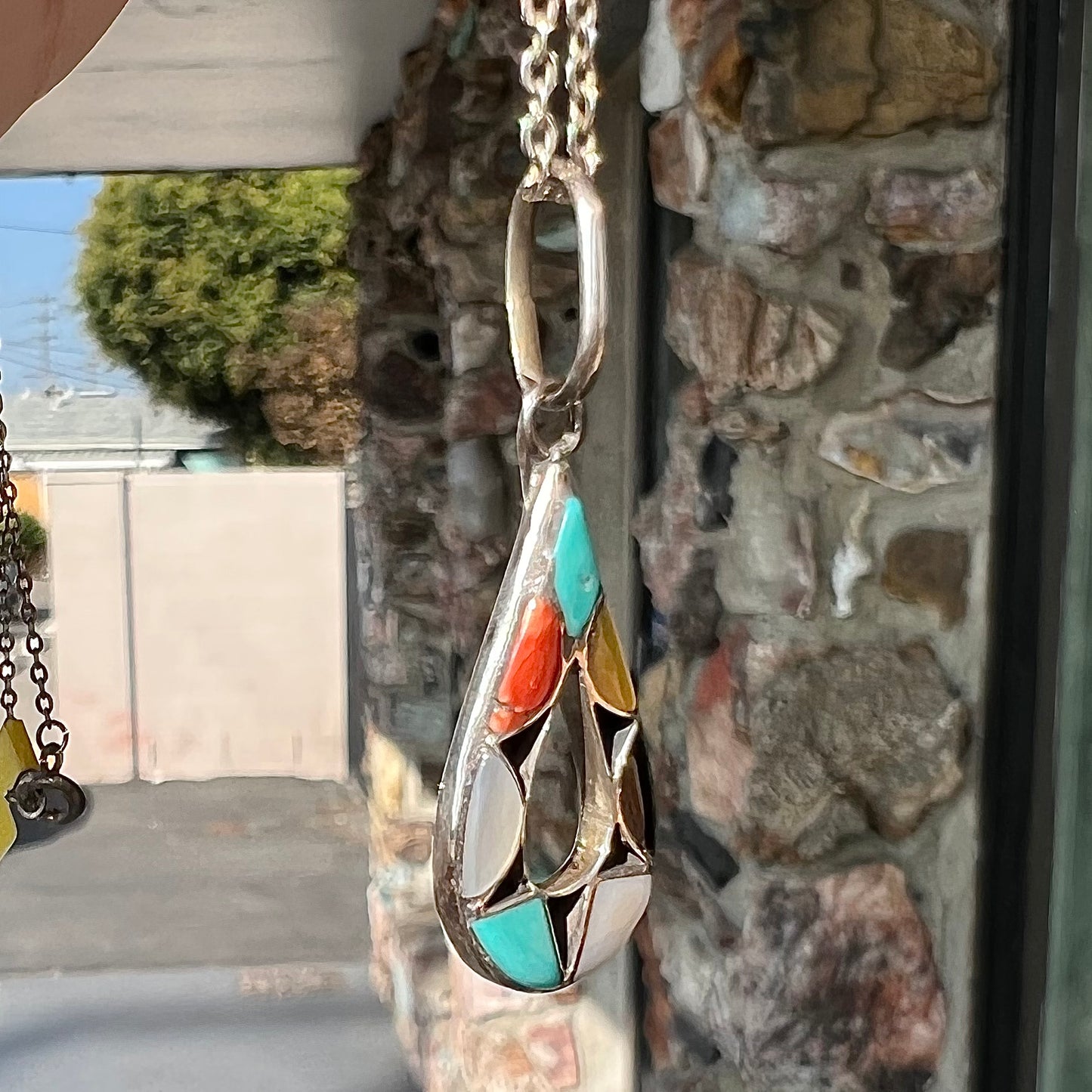 Photo of Zuni Indian pendant with stone inlay of coral, onyx, turquoise, jasper, and mother of pearl.