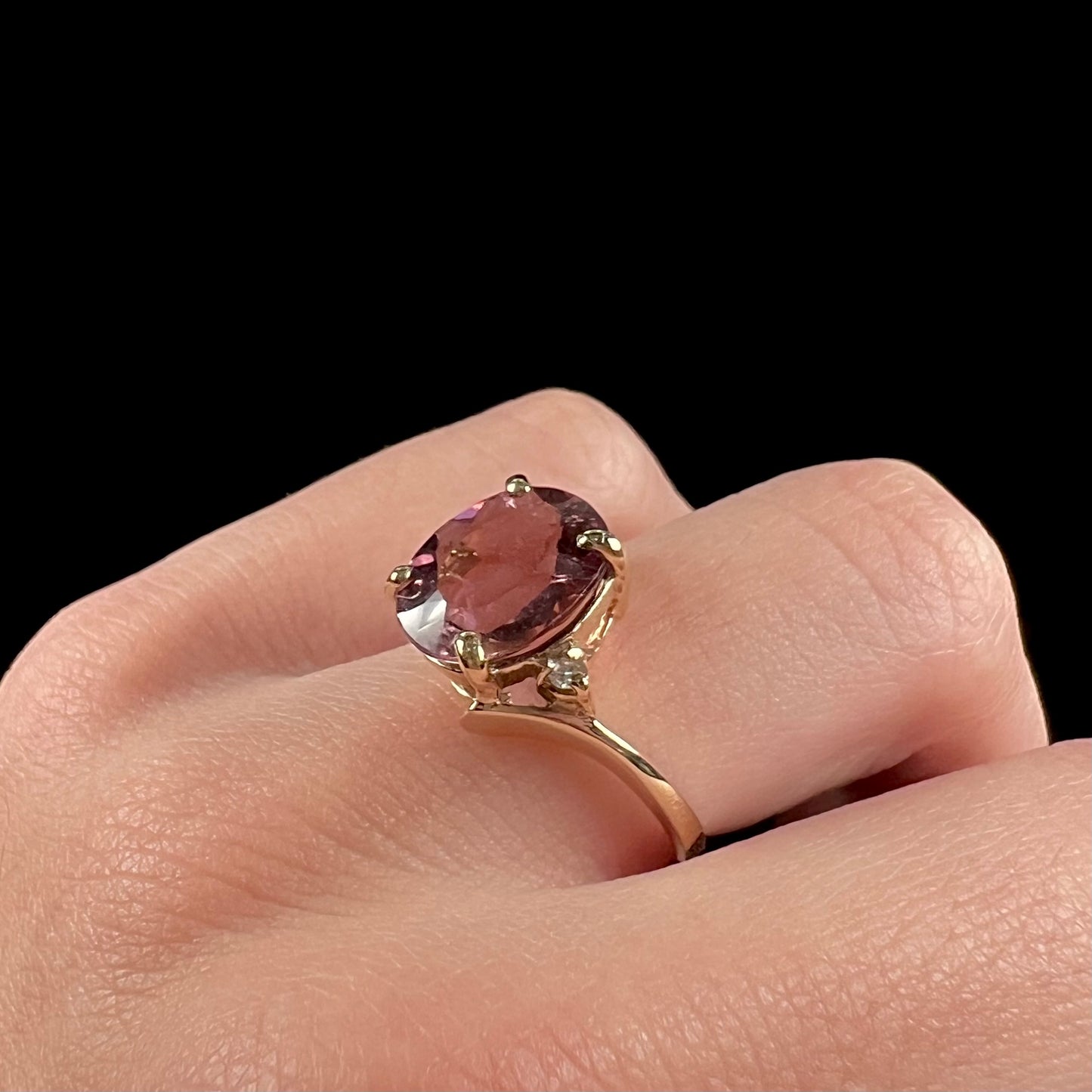 A ladies' yellow gold, faceted oval cut purple tourmaline ring set with diamond accents.