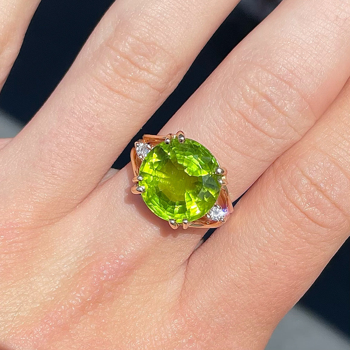 A ladies' round brilliant cut peridot statement ring set with two round diamond accents in yellow gold.