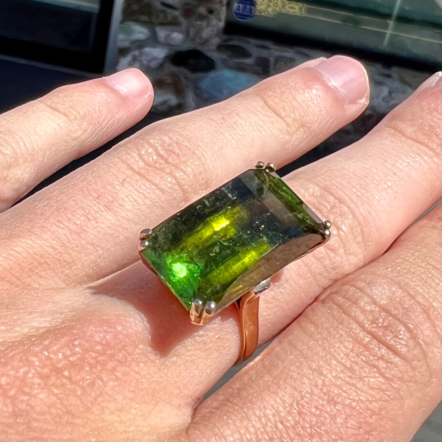 A faceted step-cut dark green tourmaline basket set solitaire ring cast in yellow gold.