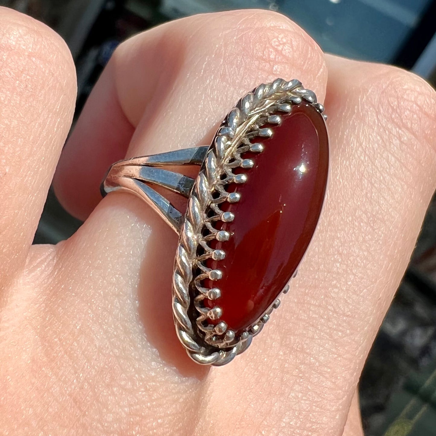A split shank silver ring set with a brown sard stone in a rope bezel with small prongs.