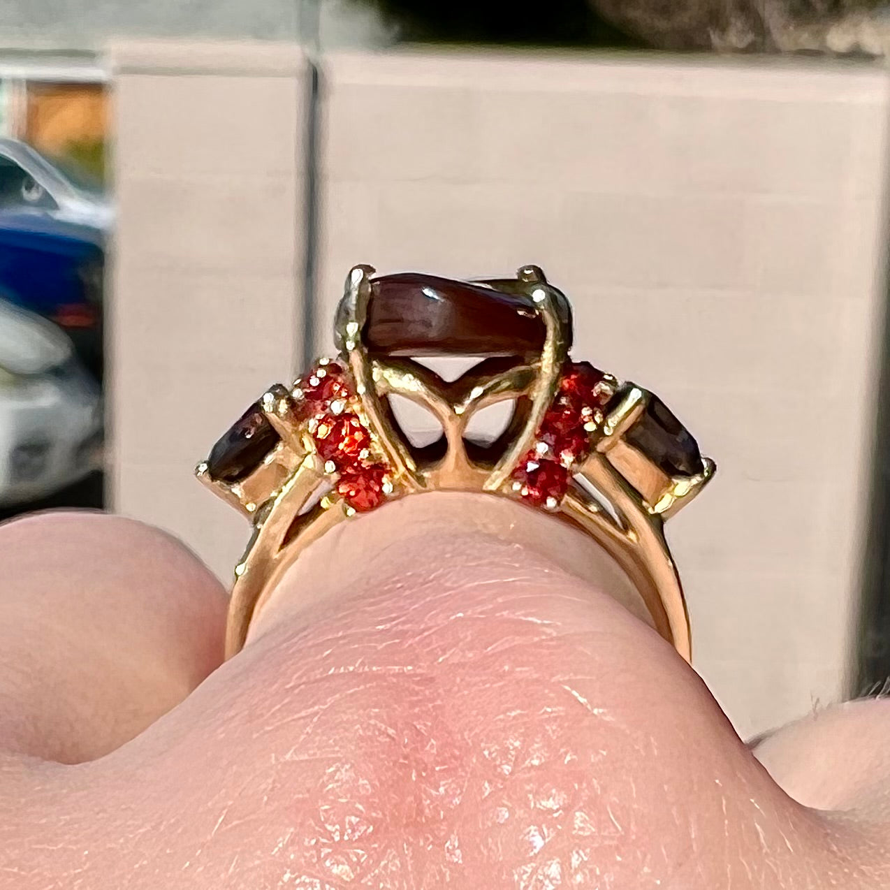 A ladies yellow gold fire agate ring set with trillion cut smoky quartz and round cut red-orange garnet accents. The fire agate displays green and red.