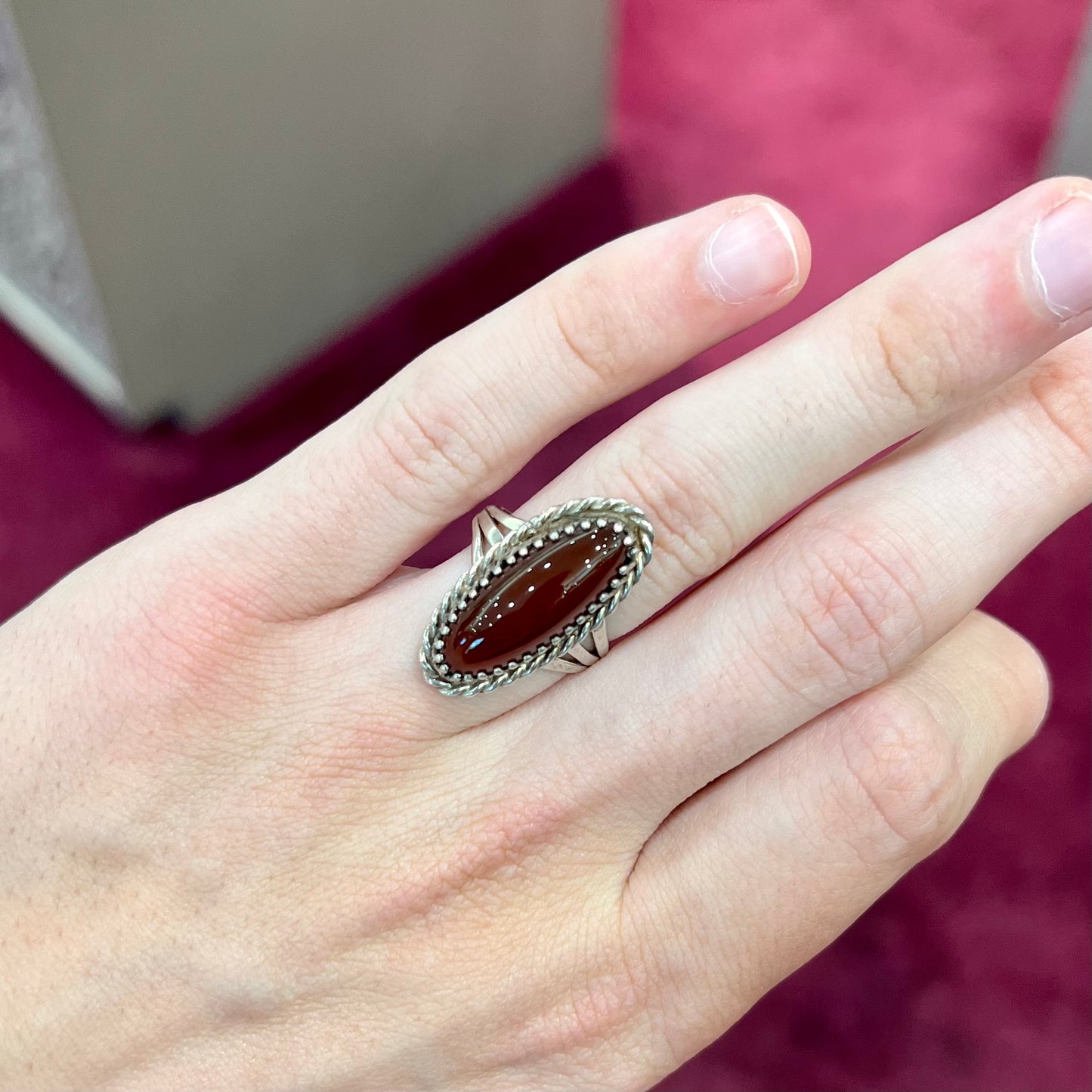 A split shank silver ring set with a brown sard stone in a rope bezel with small prongs.