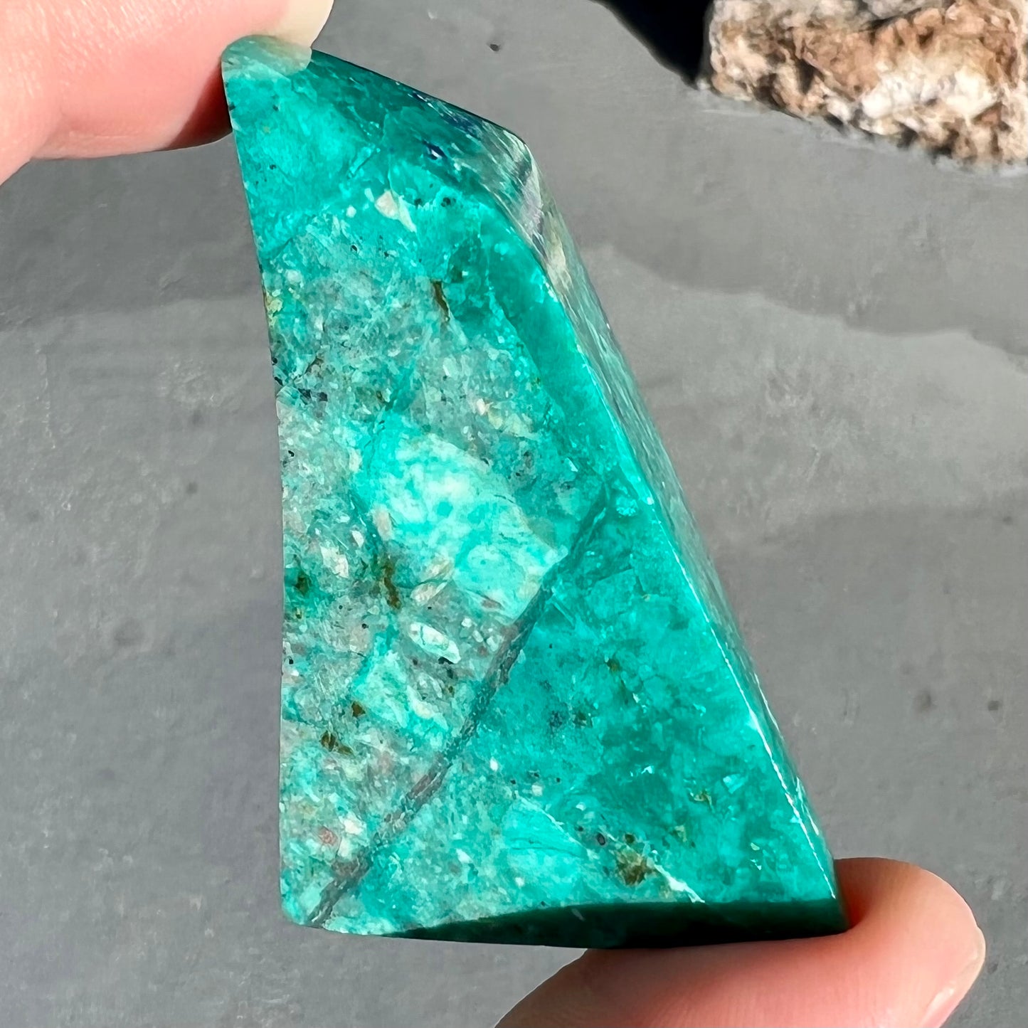 A loose polished sculpture of green chrysocolla with blue azurite inclusions.