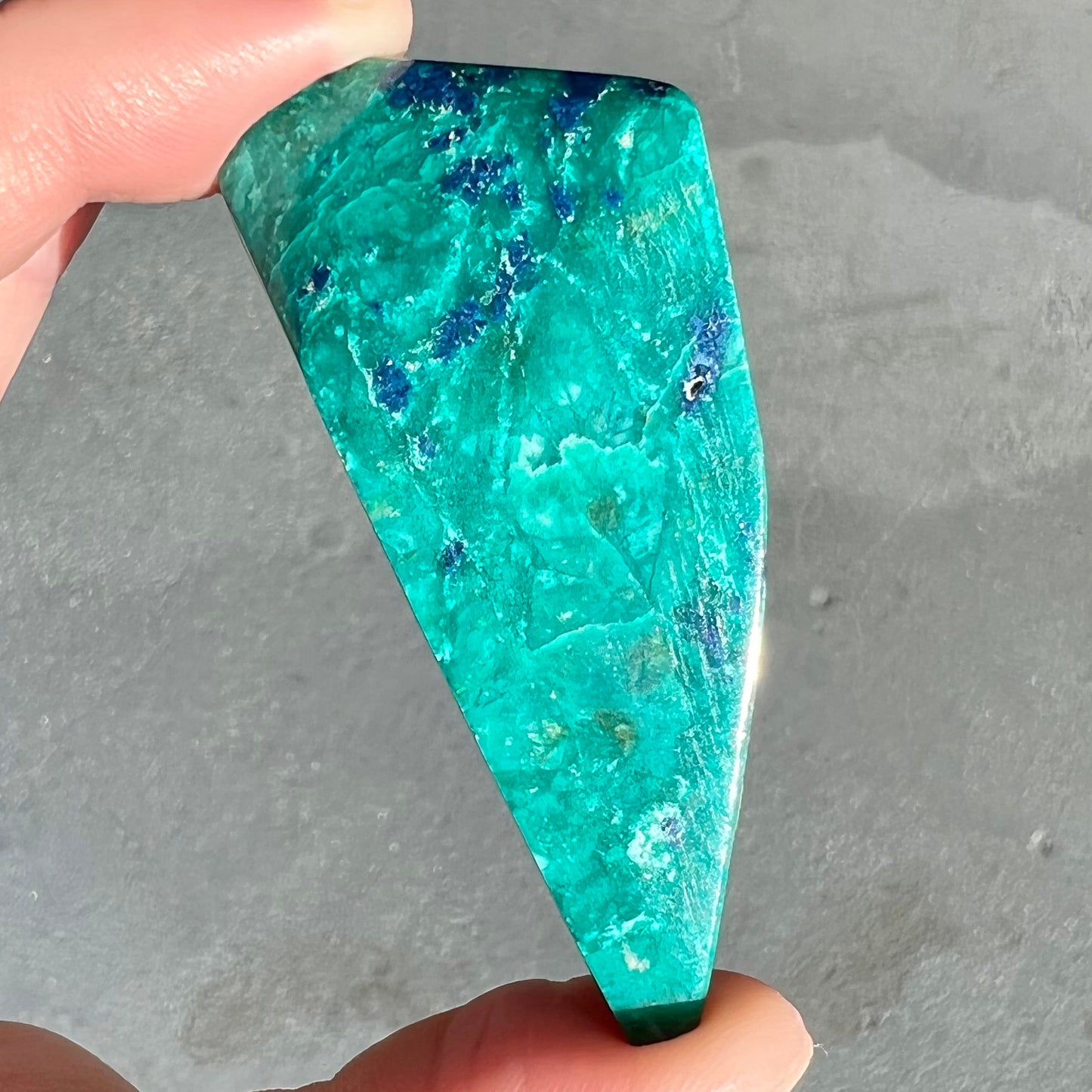 A loose polished sculpture of green chrysocolla with blue azurite inclusions.