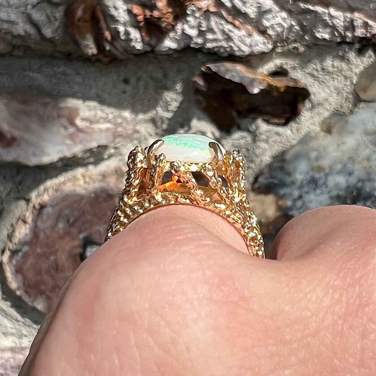 A yellow gold solitaire engagement ring set with an oval cabochon cut white crystal opal.