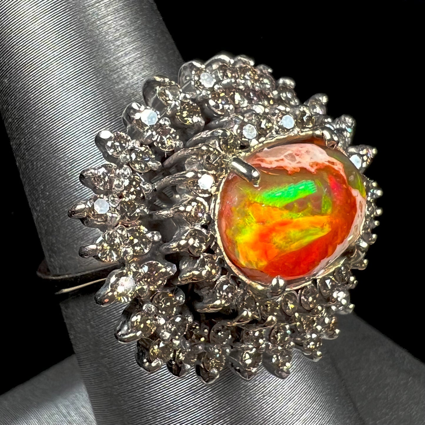 An 18k white gold orange fire opal ring set with a triple halo of diamonds.