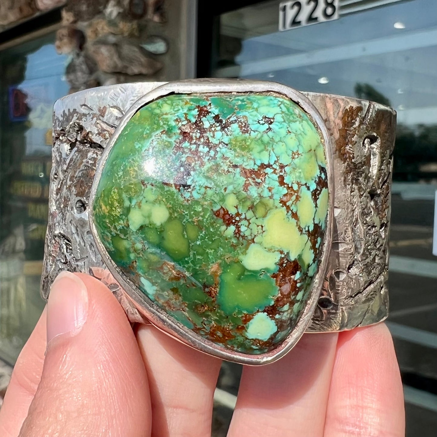 A men's sterling silver cuff bracelet infused with copper and set with a green turquoise stone from Carico Lake, Nevada.