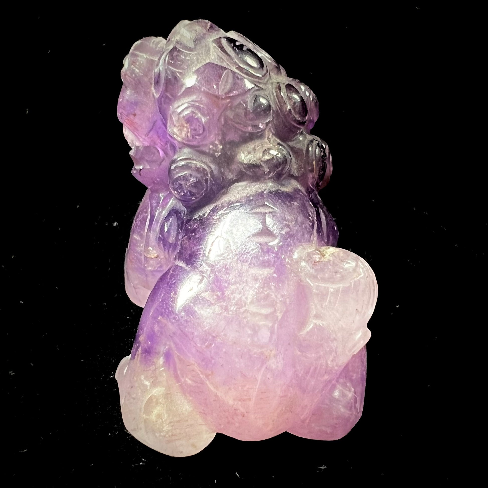 A stone foo dog carving carved from a purple Brazilian amethyst crystal.