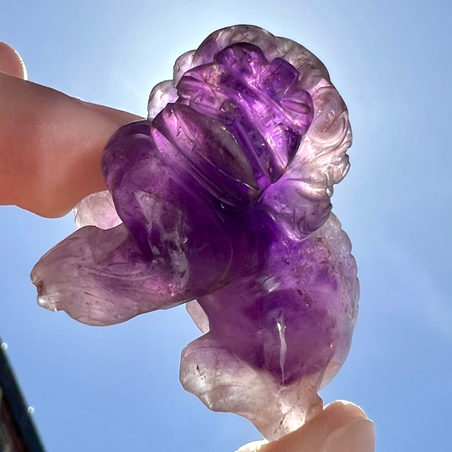 A stone foo dog carving carved from a purple Brazilian amethyst crystal.
