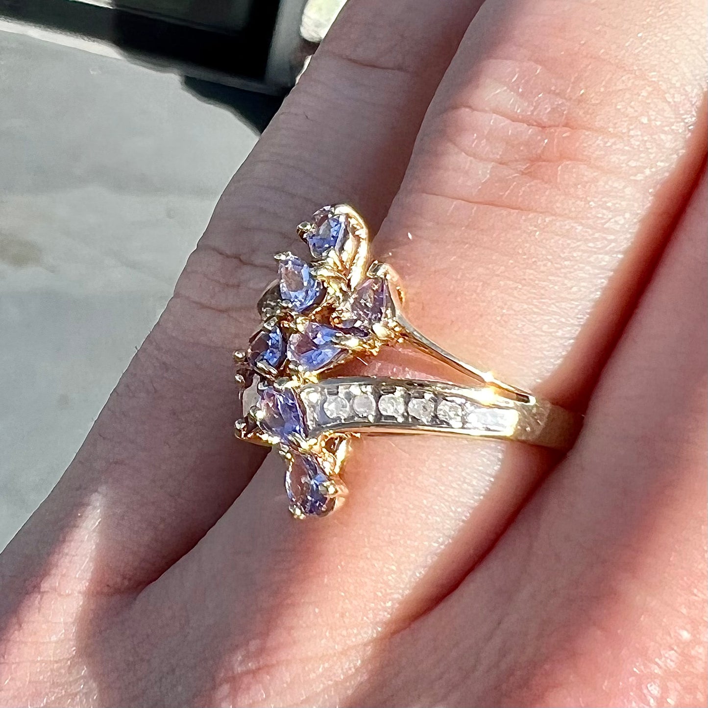 A pear shape tanzanite cluster ring channel set with diamonds in yellow gold.