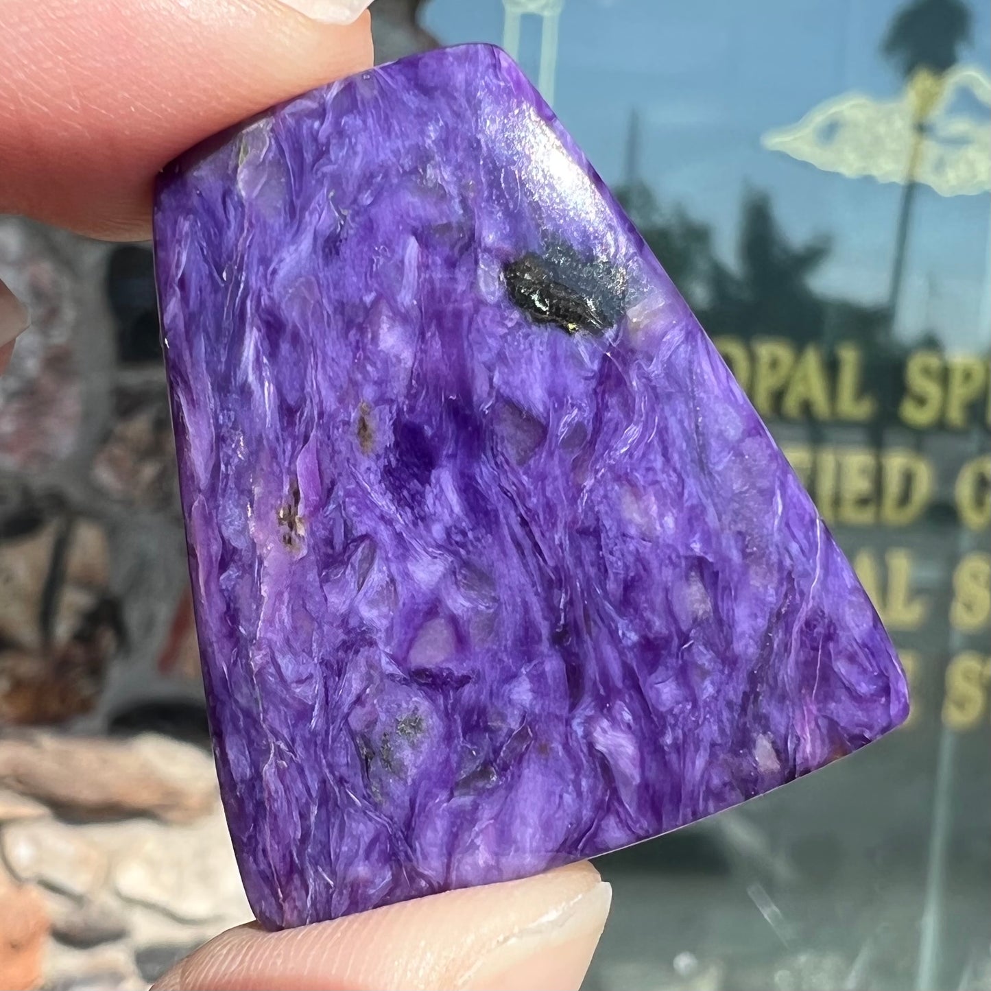 A loose, trapezoid cabochon cut purple charoite stone from Russia.