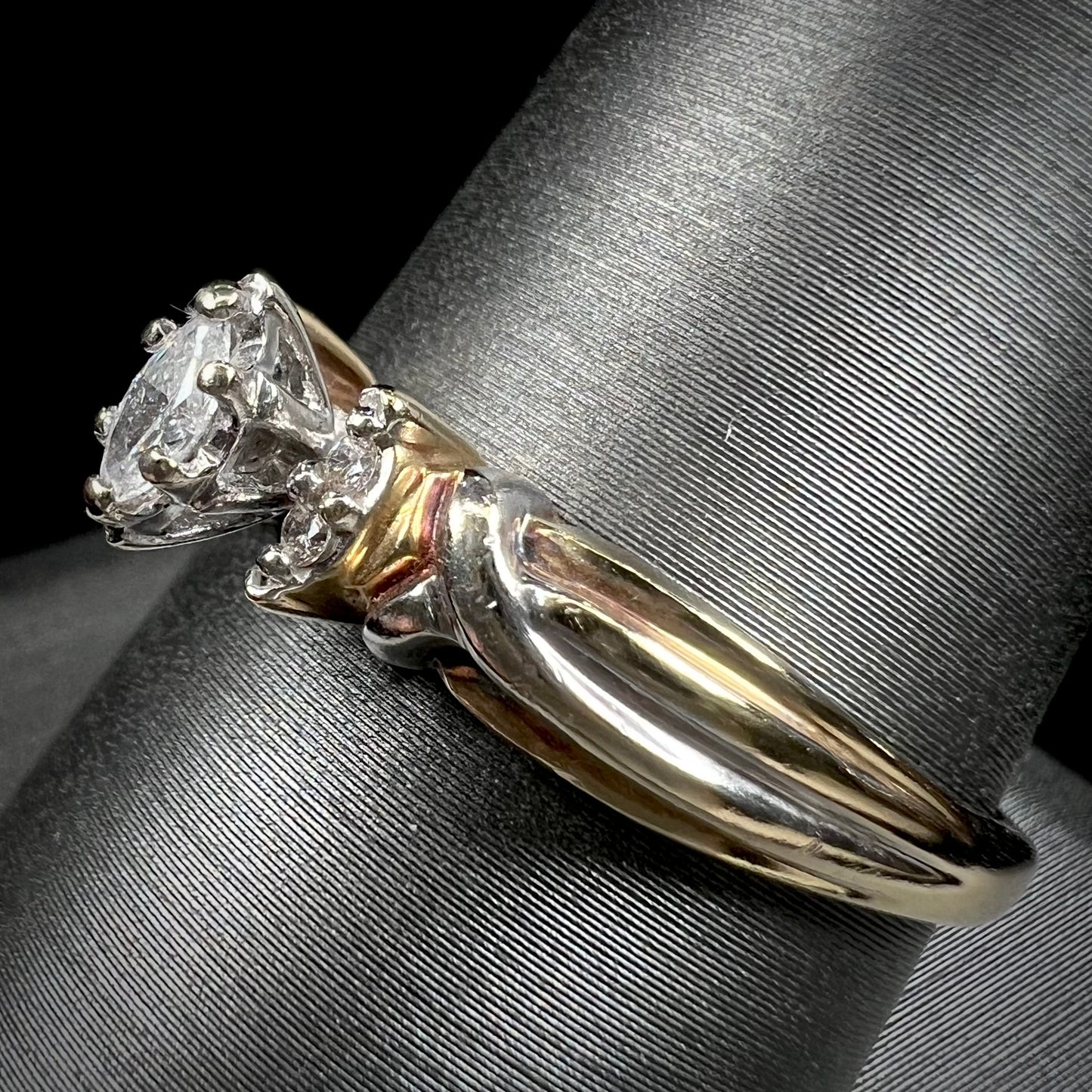 A ladies' two-tone white and yellow gold marquise cut diamond enagagement ring.  There are round diamond accents.