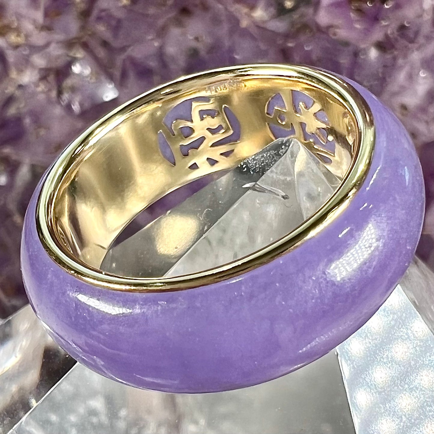 A stone ring carved from purple jadeite jade and mounted on a gold band.