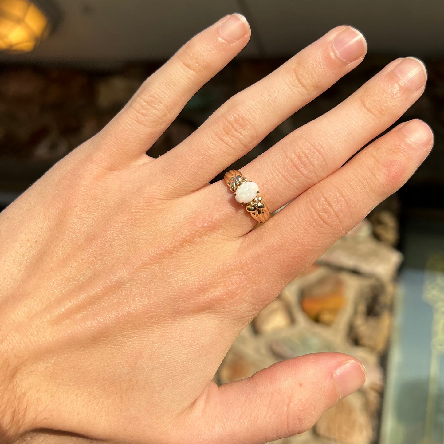 A ladies' yellow gold white crystal opal and diamond ring. The opal is prong set.