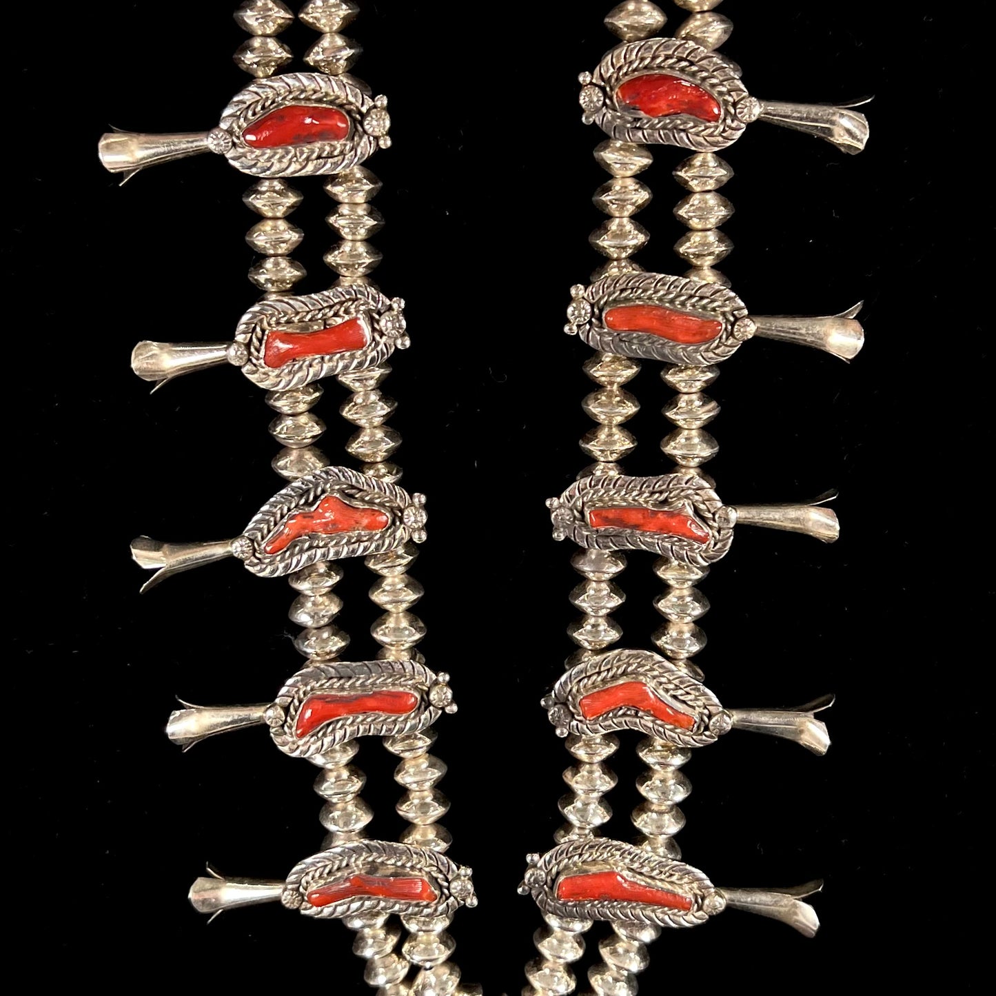 A Navajo style squash blossom necklace set with red coral branches, handmade by artist Delbert Chatter.