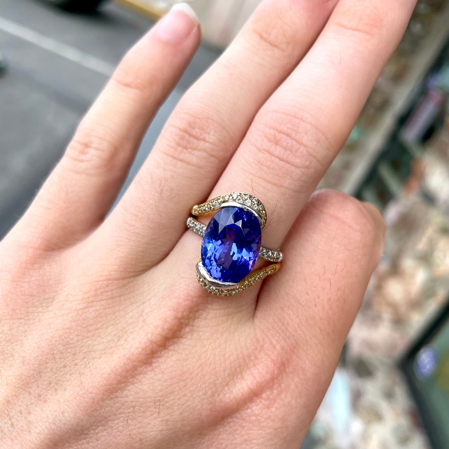 A large, oval cut blue tanzanite set in a two tone yellow and white gold diamond ring.