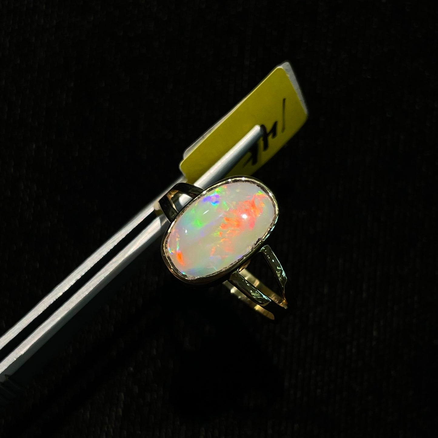 A handmade split shank white opal solitaire ring in yellow gold.