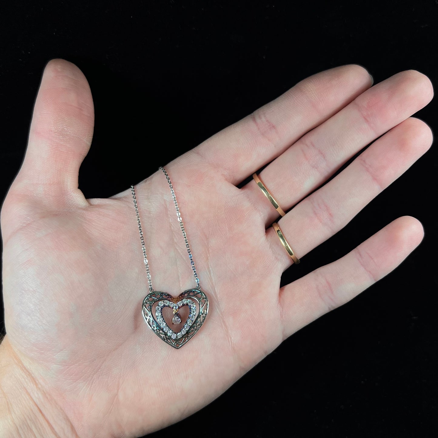 A sterling silver and cubic zirconia heart necklace. The silver has a rainbow patina.