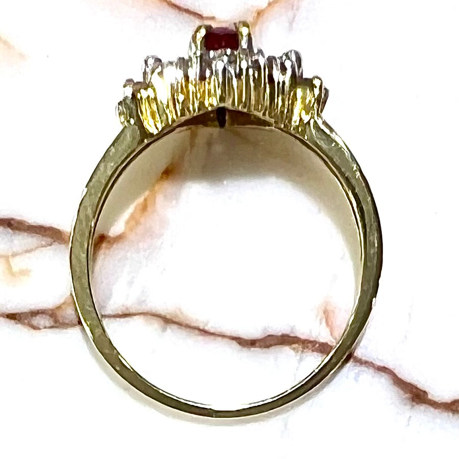A yellow gold ring set with an oval cut red spinel and diamond rounds and baguettes.