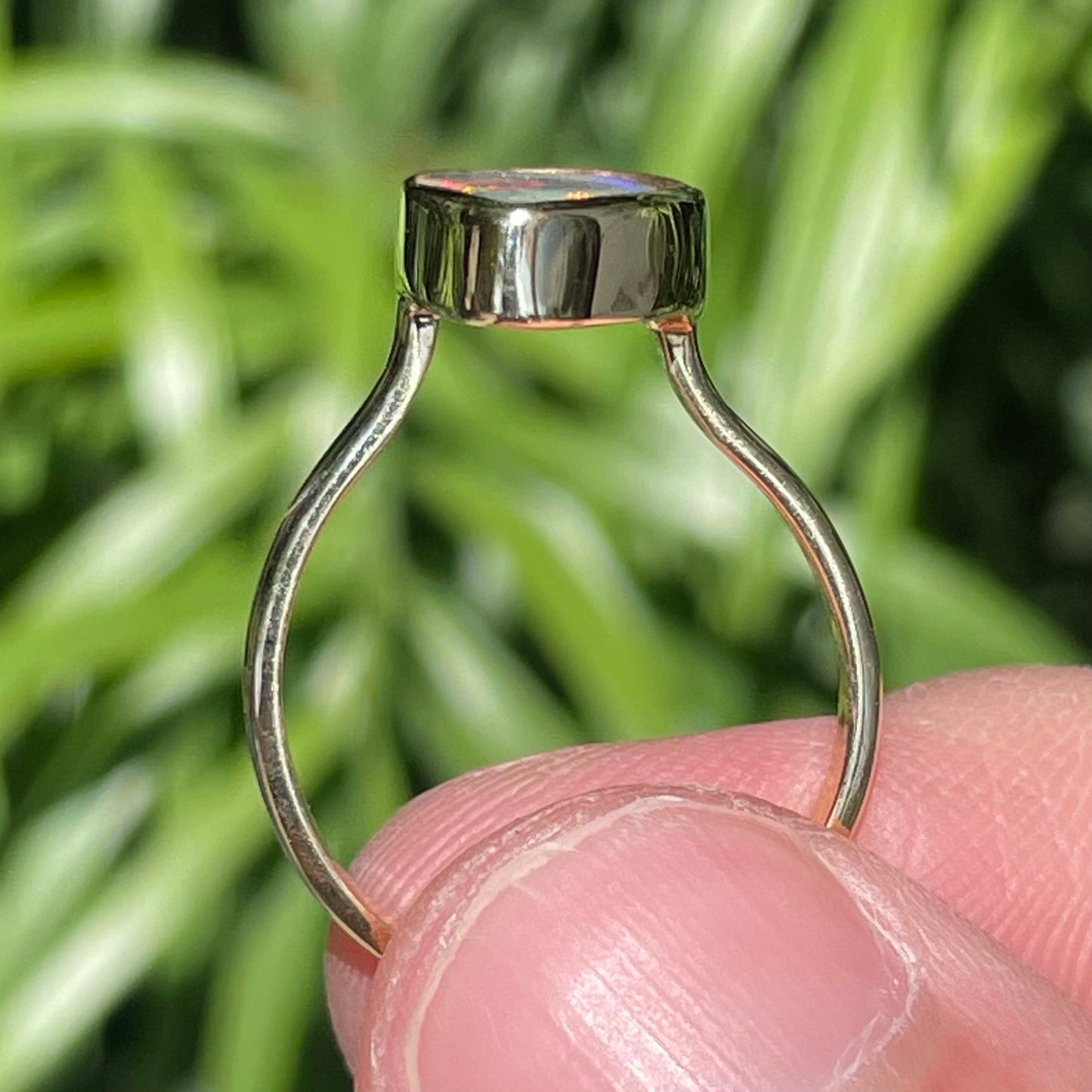 A freeform cut semi-black opal from Lightning Ridge, Australia set in a bezel set yellow gold solitaire ring.