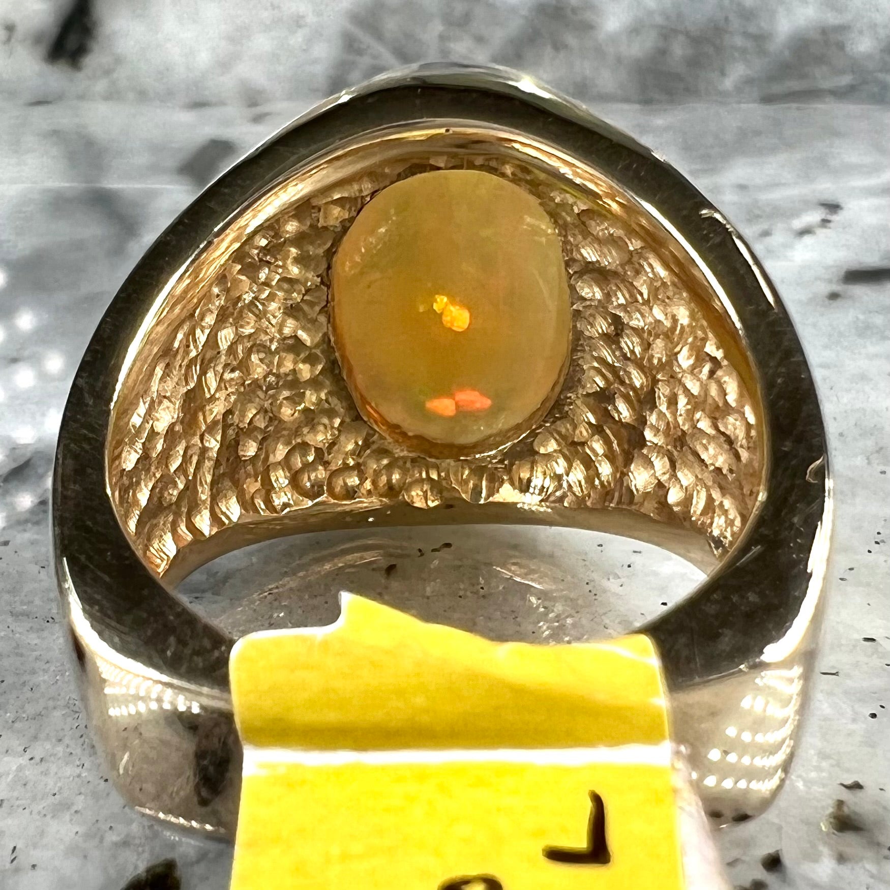 A solid yellow gold solitaire men's fire opal ring.  The stone is an orange oval cabochon cut.