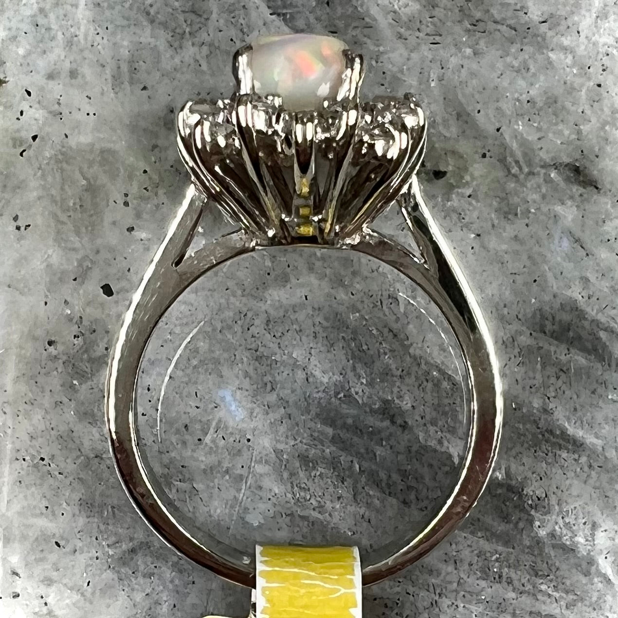 A white crystal opal ring cast in white gold with a halo of round cut diamonds.