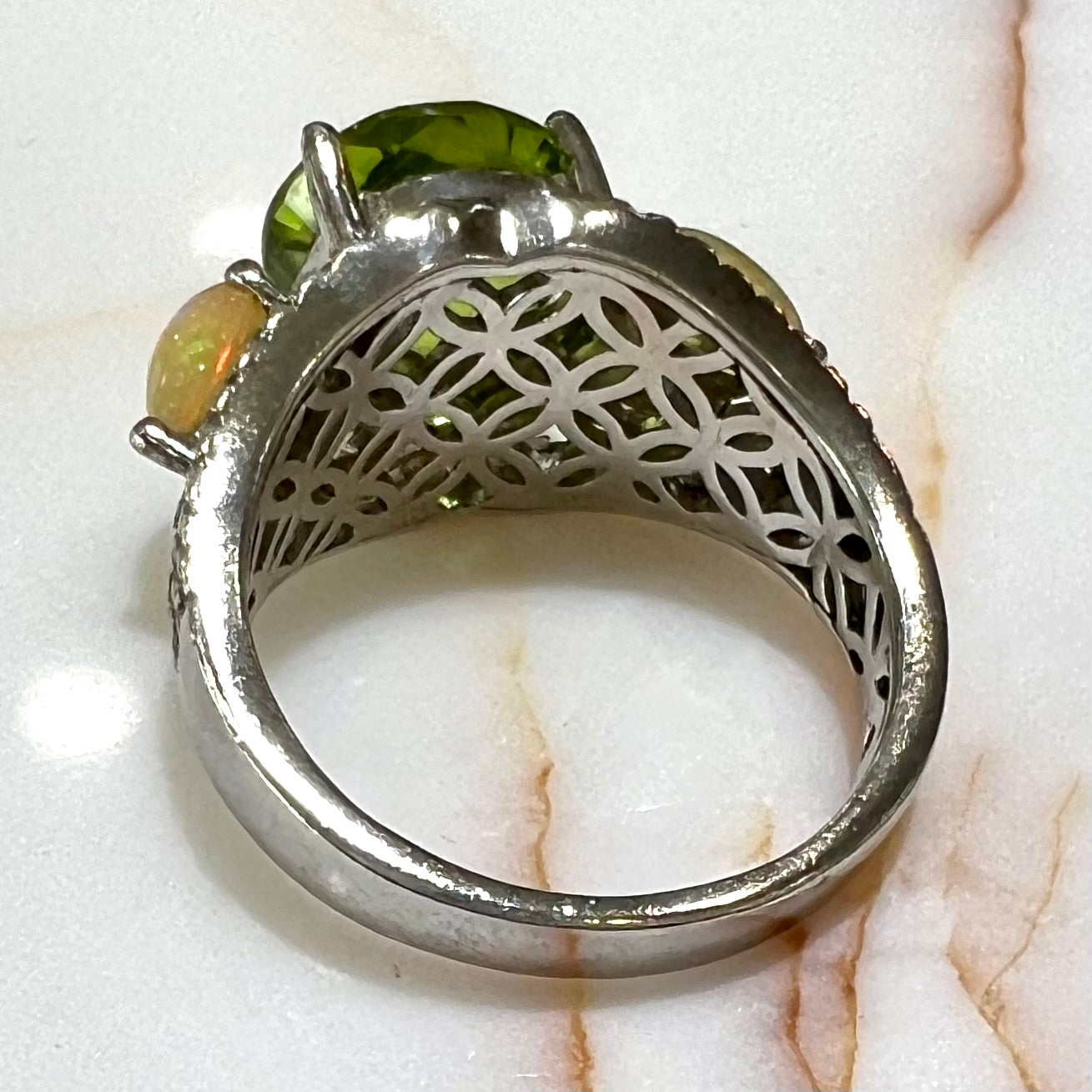 A sterling silver ring set with one large round peridot stone set between two pear shape cabochon Ethiopian opals. Cubic zirconia stones line the ring.