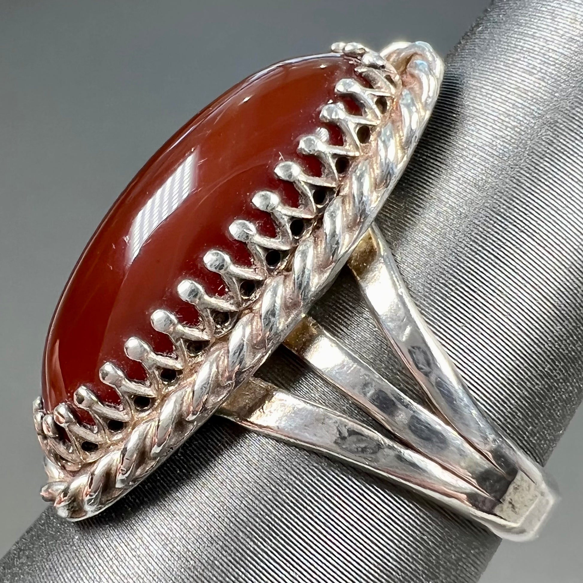 A split shank silver ring set with a brown sard stone in a rope bezel with small prongs.