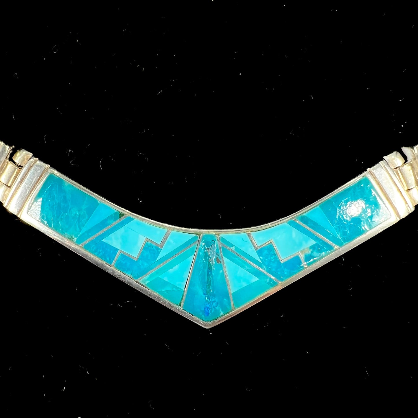 A silver omega style necklace inlaid with turquoise under the watch of David Rosales.