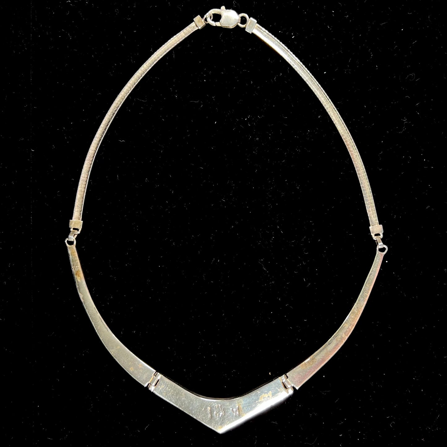 A silver omega style necklace inlaid with turquoise under the watch of David Rosales.