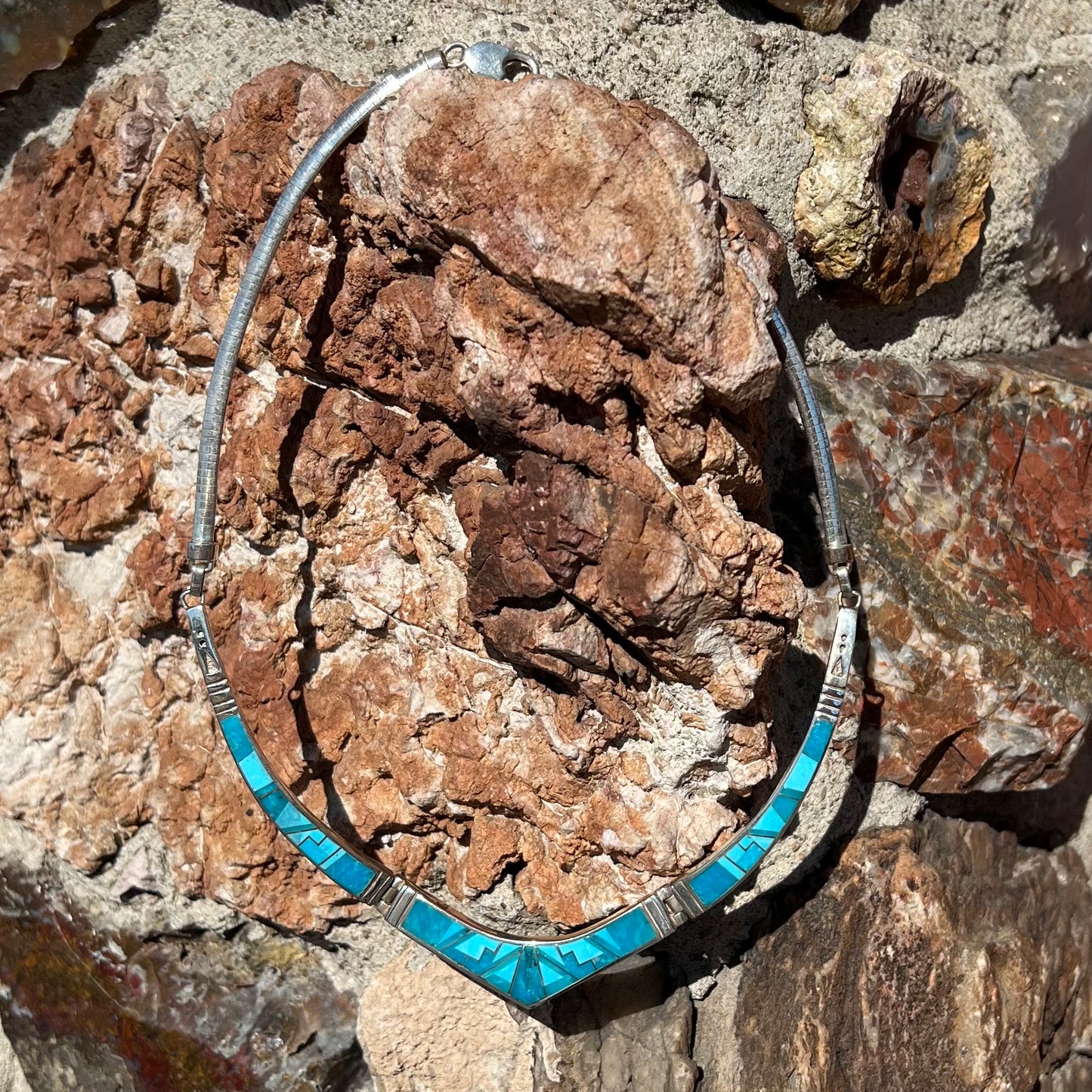 A silver omega style necklace inlaid with turquoise under the watch of David Rosales.