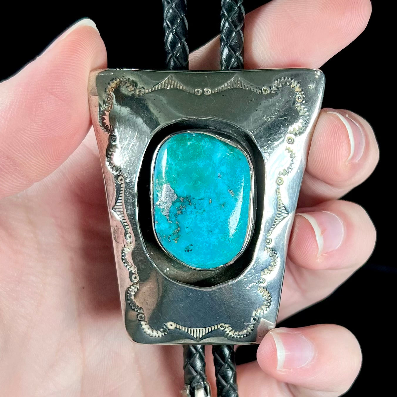 A vintage sterling silver Navajo bolo tie set with Morenci turquoise, handmade by artist Delvin Nelson.