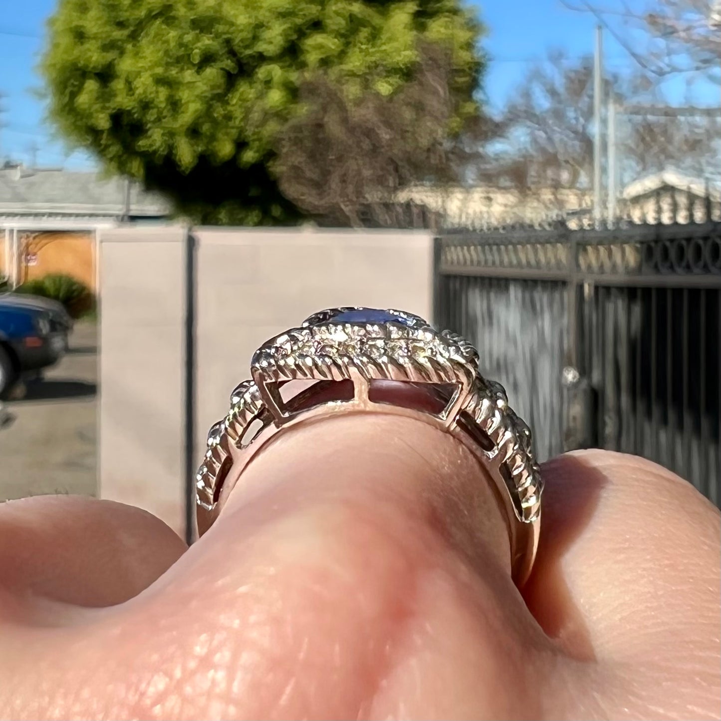 A white gold trillion cut tanzanite ring set with a diamond halo and diamond accents.