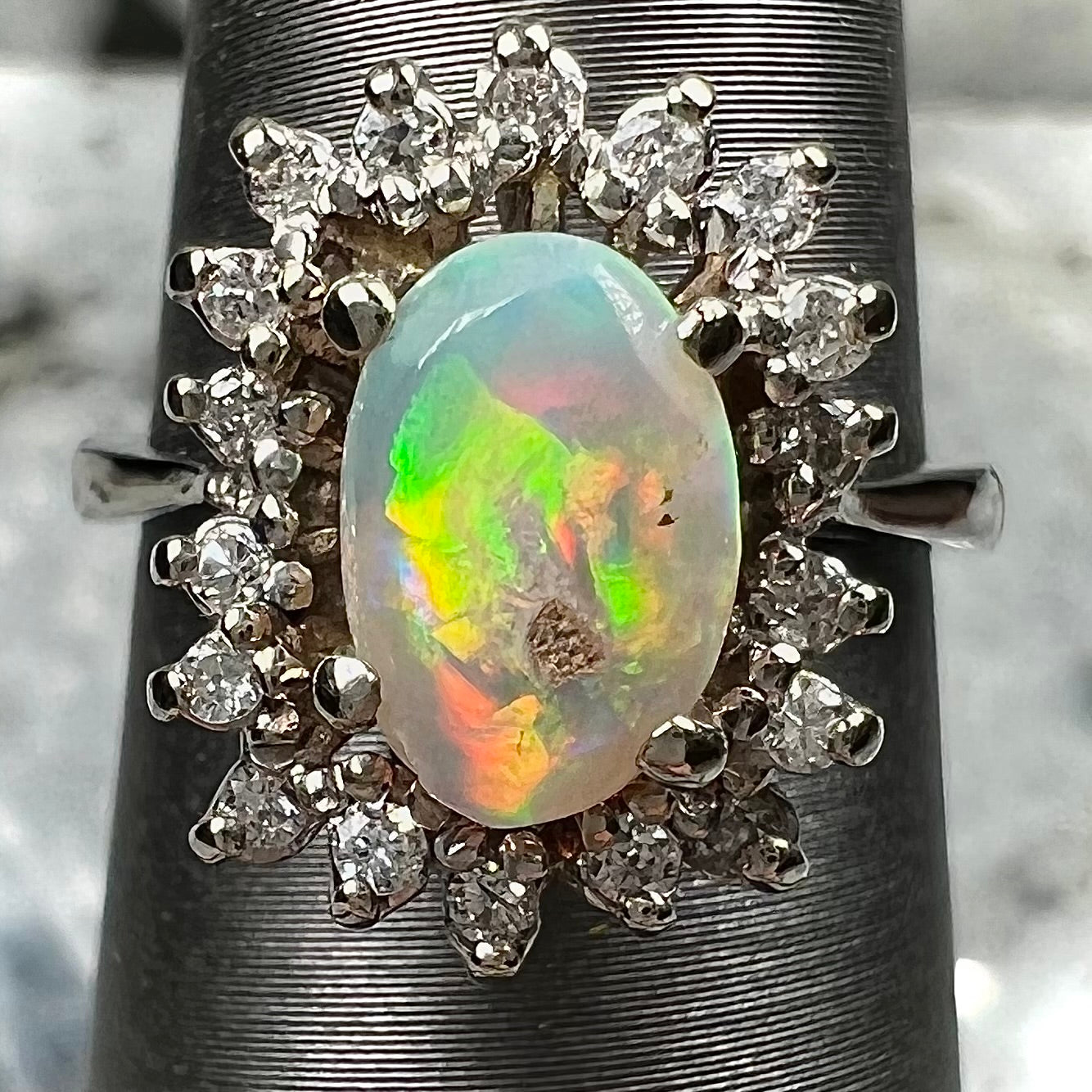 A white crystal opal ring cast in white gold with a halo of round cut diamonds.