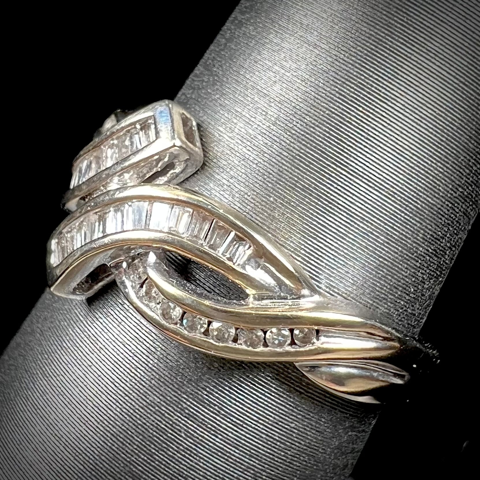 A ladies' white gold crisscross style ring channel set with round and baguette cut diamonds.