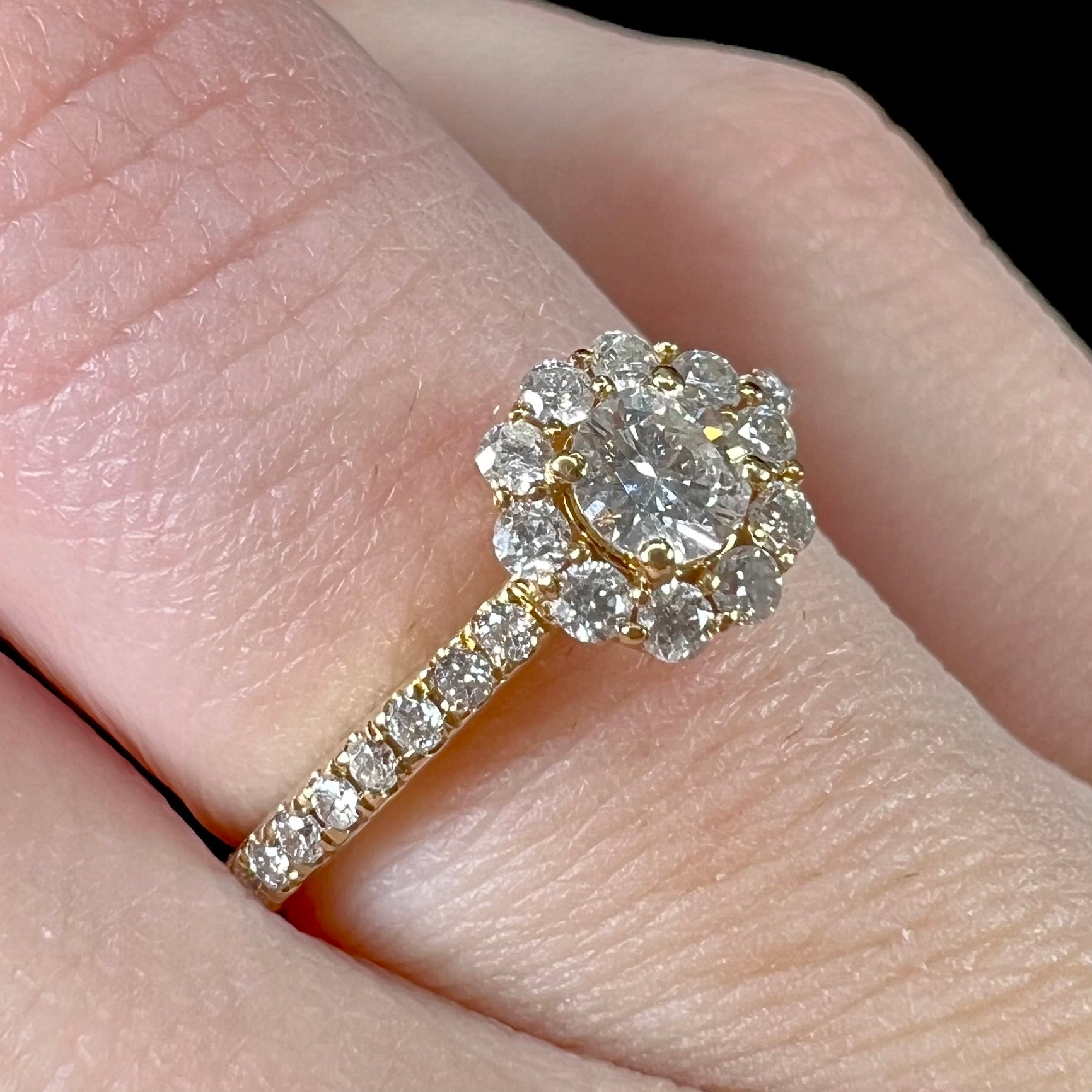 A ladies' diamond halo engagement ring cast in yellow gold.  The center stone is a 0.19ct round cut natural diamond.