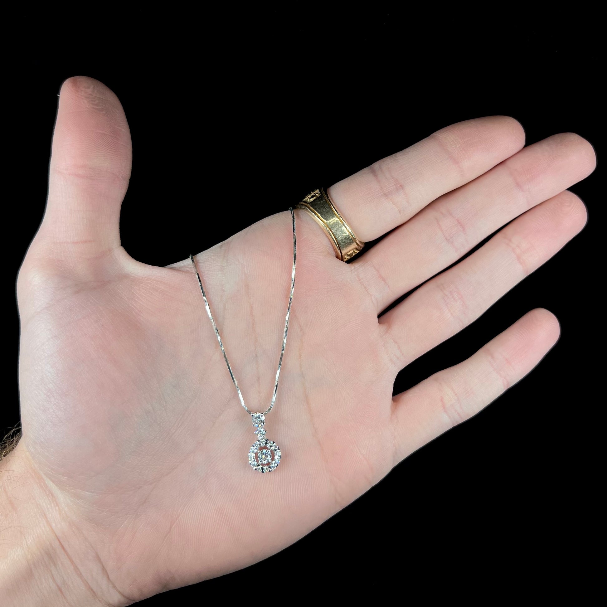 A ladies' diamond halo necklace with snake chain cast in platinum.