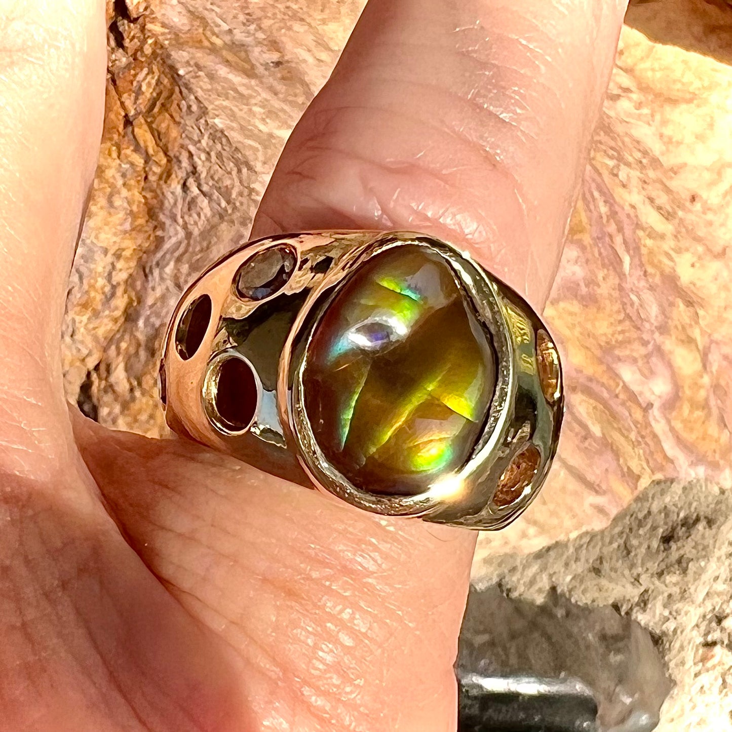 Men's rainbow fire agate ring set in yellow gold with champagne diamonds. The ring style has holes.