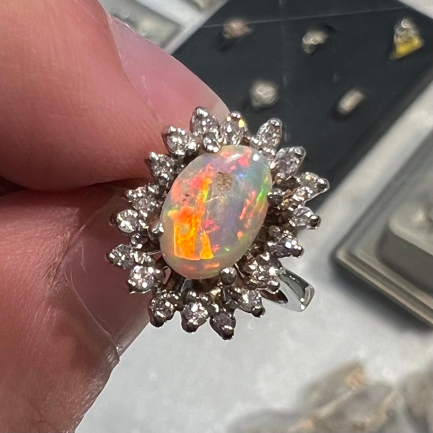 A white crystal opal ring cast in white gold with a halo of round cut diamonds.