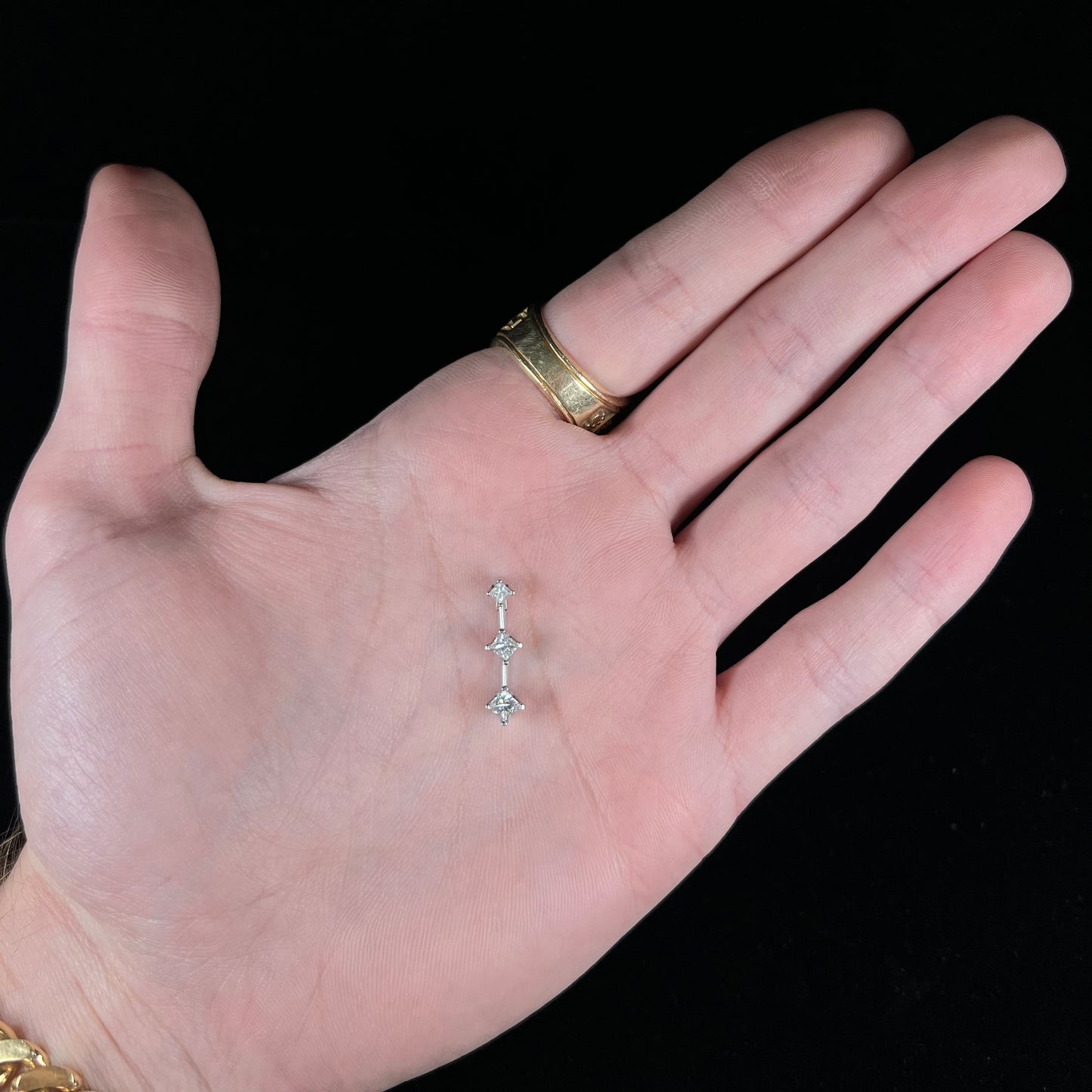 A ladies' white gold three stone drop pendant set with princess cut diamonds. There are two points of articulation.