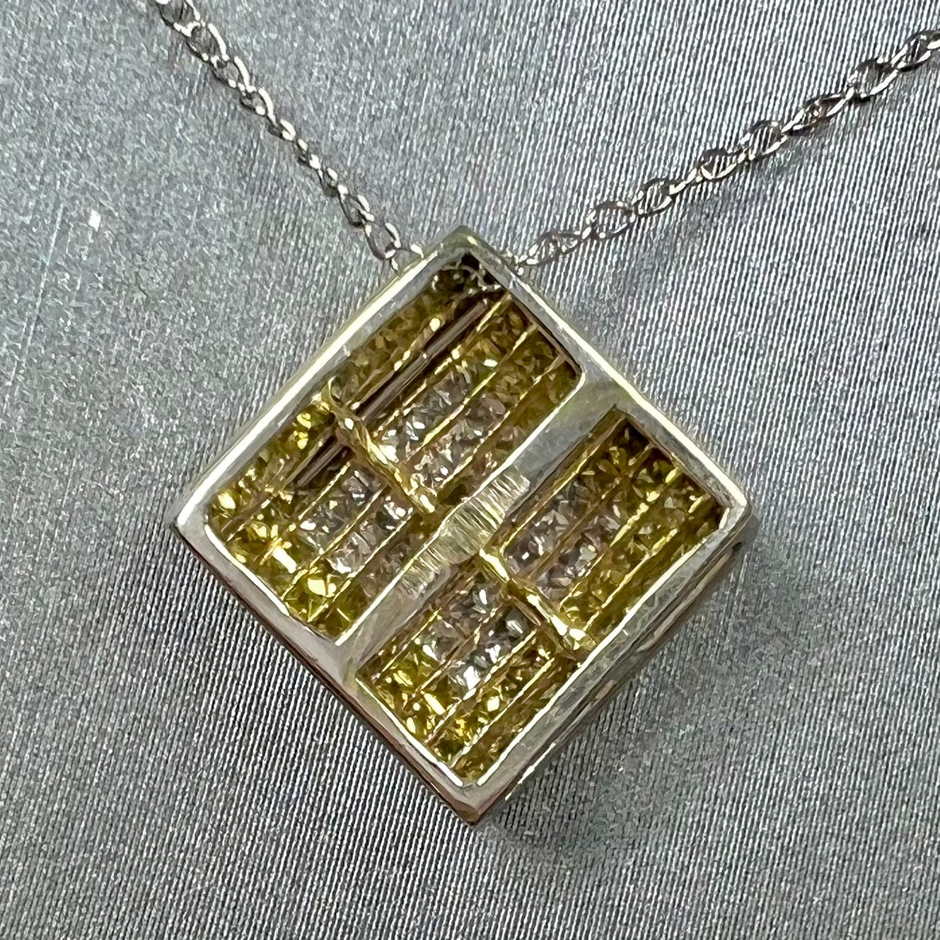 A square shaped necklace set with princess cut yellow and white diamonds in a white gold setting on a white gold chain.