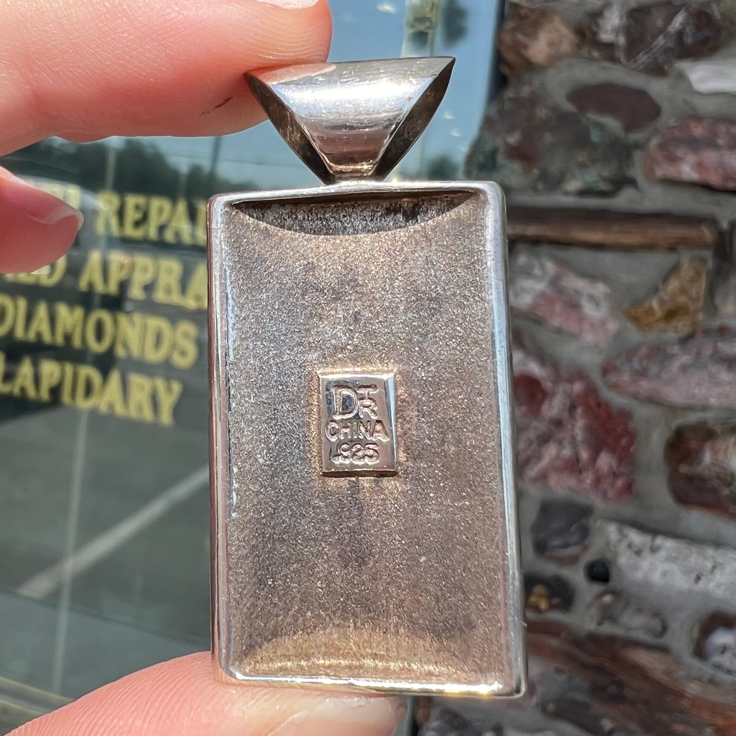 A silver pendant set with square cabochon cut turquoise and coral stones. The piece is stamped "DTR CHINA".