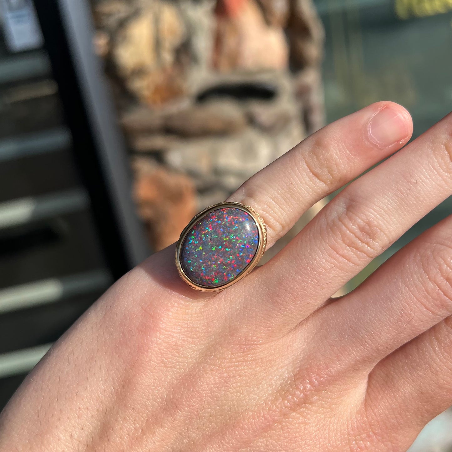 A bright black Andamooka opal that displays a pinfire pattern set in a vintage-style yellow gold bezel ring.